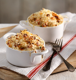 Creamy Chicken Veggie Bake in single serving crochettes sitting on a dish towel on top of a wooden tray