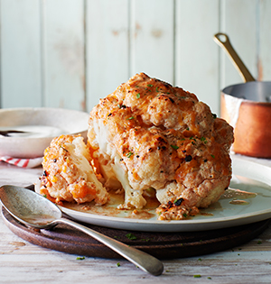 Whole Roasted Cauliflower on a plate with a spoon
