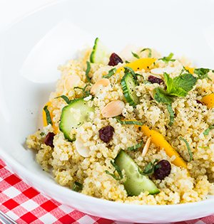 Curried Quinoa Salad made with Astro Yogurt served in a white bowl sitting on a red and white checked tablecloth